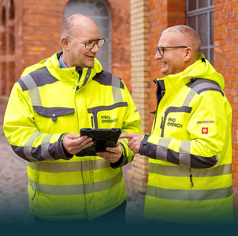 Zwei Pro Energy Techniker mit Tablet vor einem Backsteingebäude